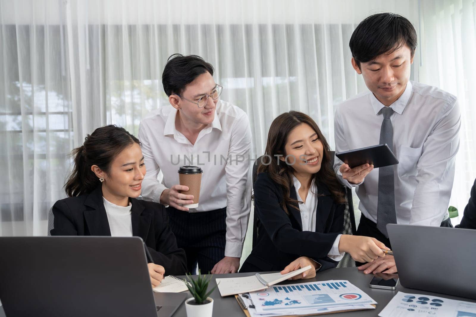 Harmony in office concept as business people analyzing dashboard paper together in workplace. Young colleagues give ideas at manager desk for discussion or strategy planning about project.