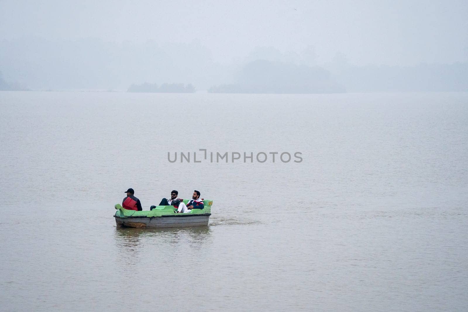 people enjoying a pedal boat decorated beautifully on the landmark sukhna lake in chandigarh with more boats in the distance showing this popular tourist spot by Shalinimathur