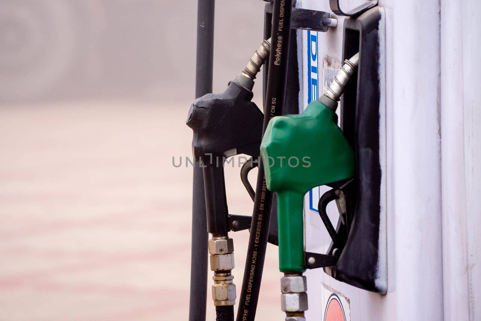 old damaged fuel pump nozzle showing petrol and deisel in india as the price increases and electric vehicles take over by Shalinimathur