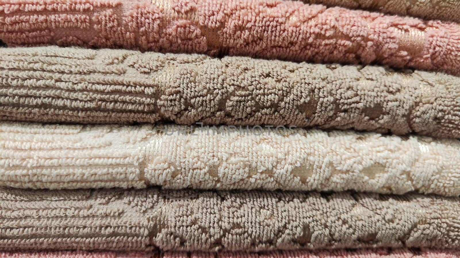 Abstract background and texture from a stack of colored soft terry towels. Lots of colorful bath towels stacked on each other. Cotton towels for hotels, home, bathroom, kitchens