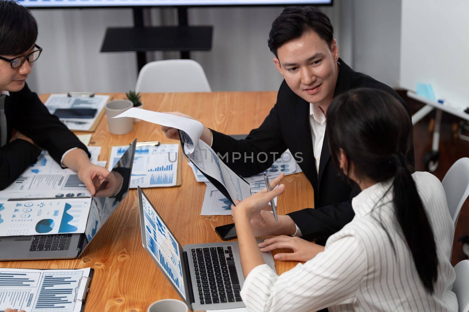 Harmony in office concept as business people analyzing dashboard paper together in workplace. Young colleagues give ideas at manager desk for discussion or strategy planning about project.
