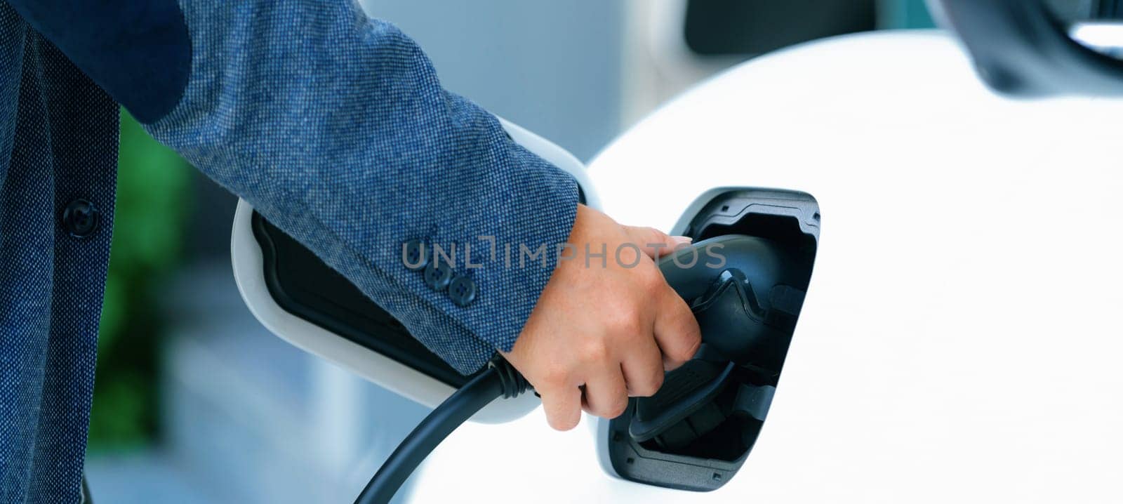 Progressive concept of hand insert an emission-free power connector to the battery of electric vehicle at home. Electric vehicle charging via cable from charging station to EV car battery