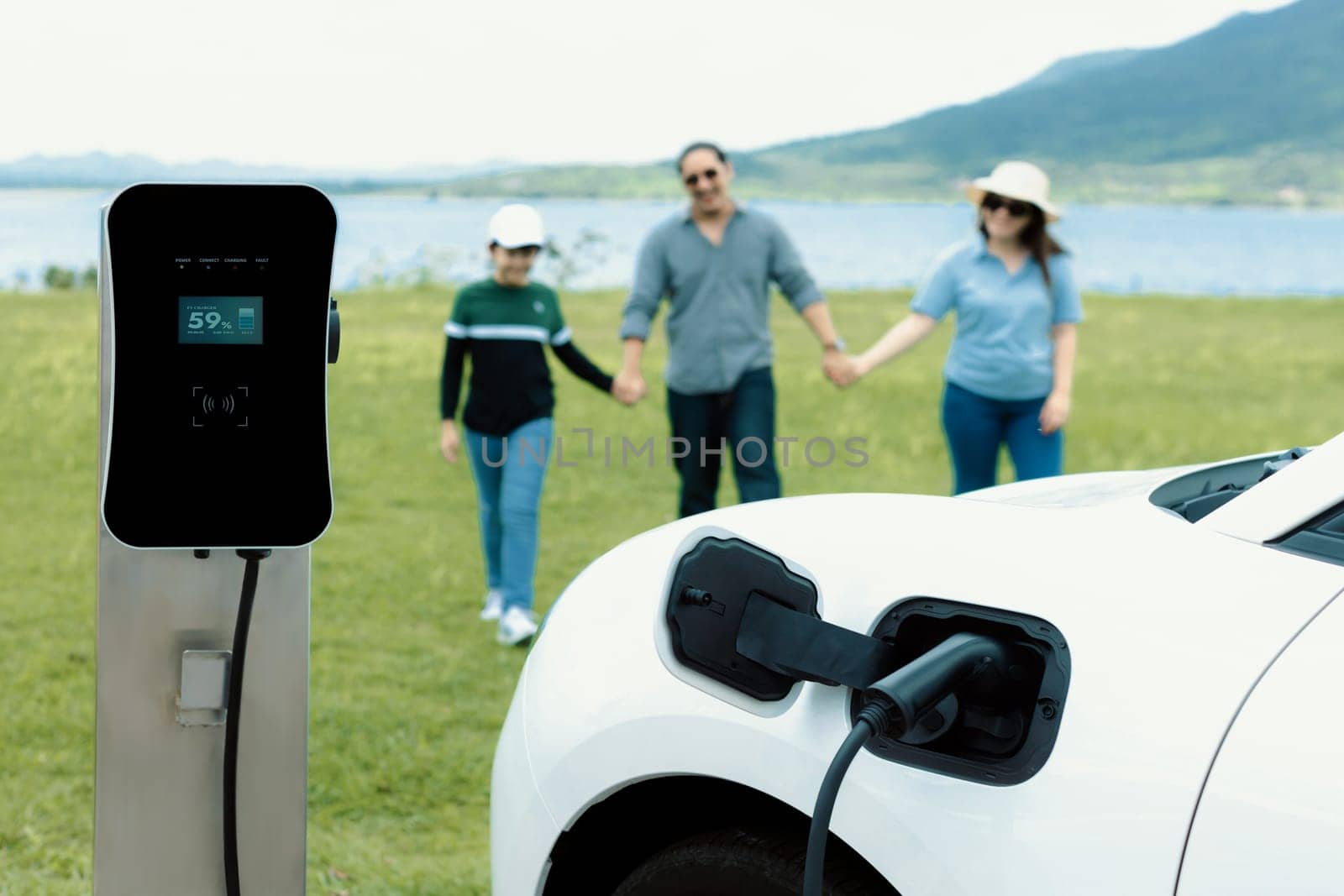 Concept of progressive happy family at green field, lake with electric vehicle. by biancoblue