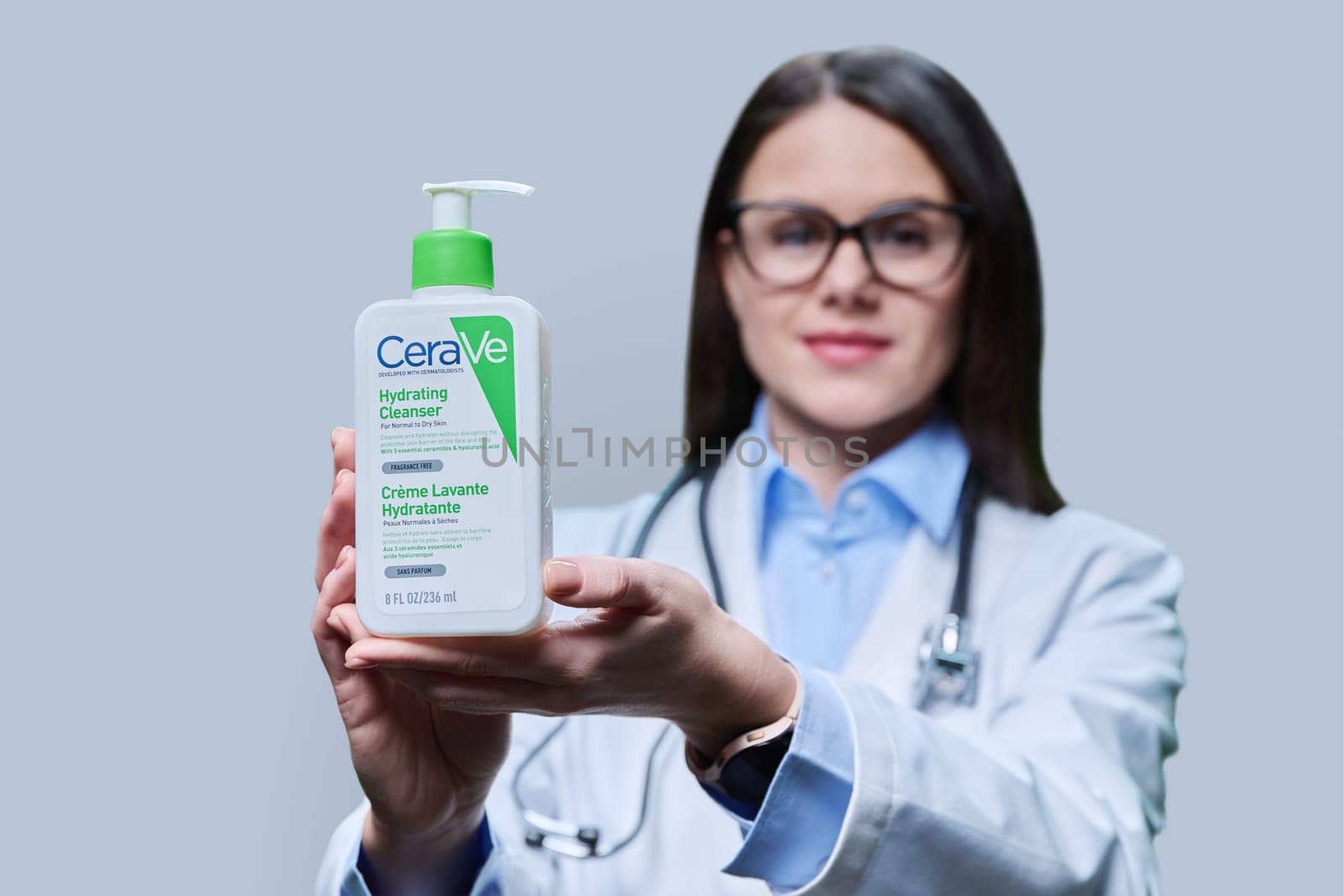 Kyiv, Ukraine, 01.03.2023, Pharmacy dermocosmetics, doctor dermatologist recommending cleansing moisturizing emulsion CeraVe, hydrating cleanser for normal to dry skin, on light gray studio background