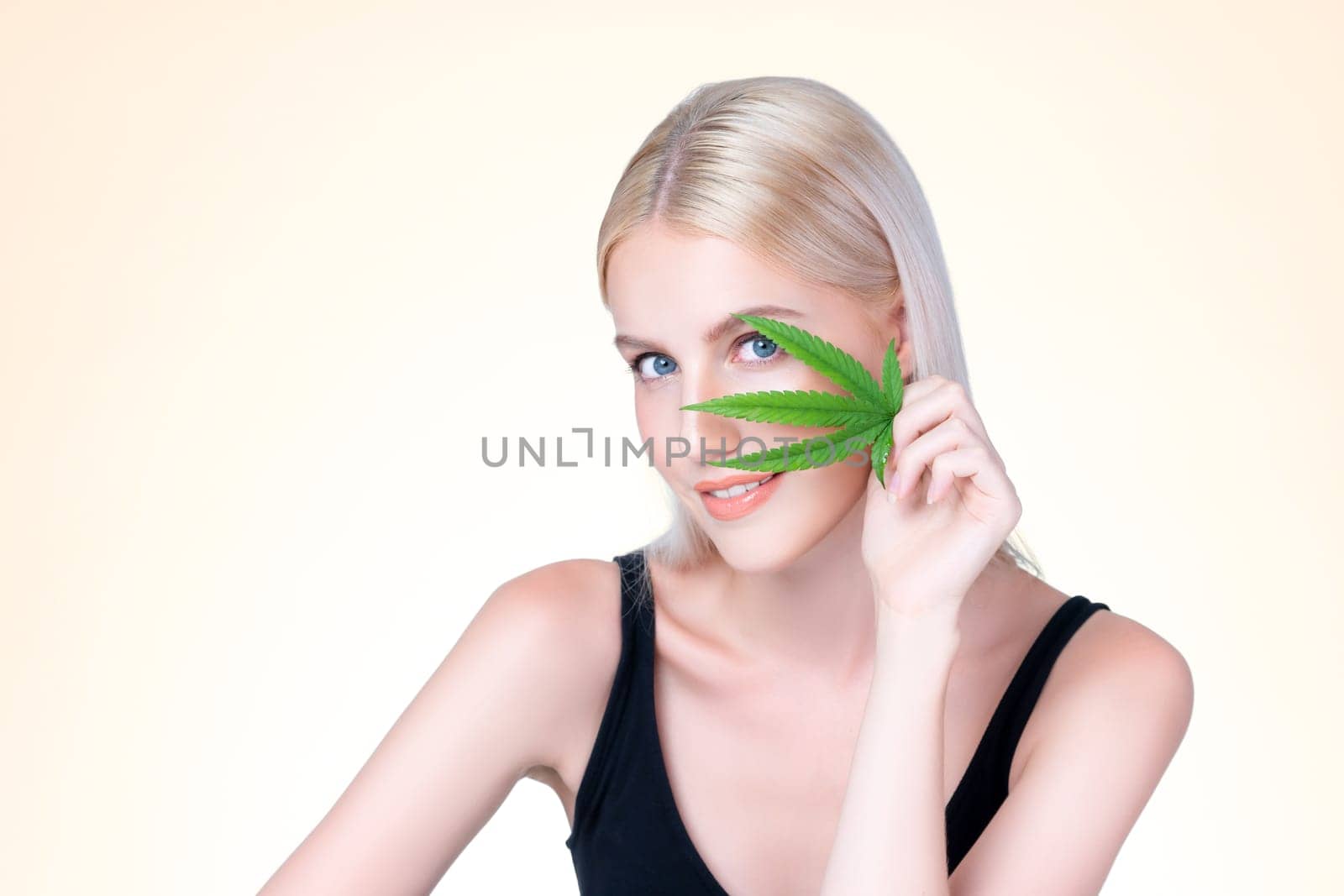 Personable beautiful white blond hair with perfect smooth makeup skin hold cannabis green hemp in isolated background for natural CBD skincare treatment with expressive facial and gesture expression.