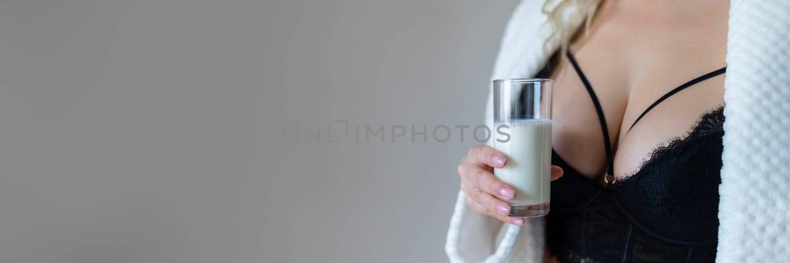sexy young woman in black lingerie pouring milk on body isolated on grey by malyshph