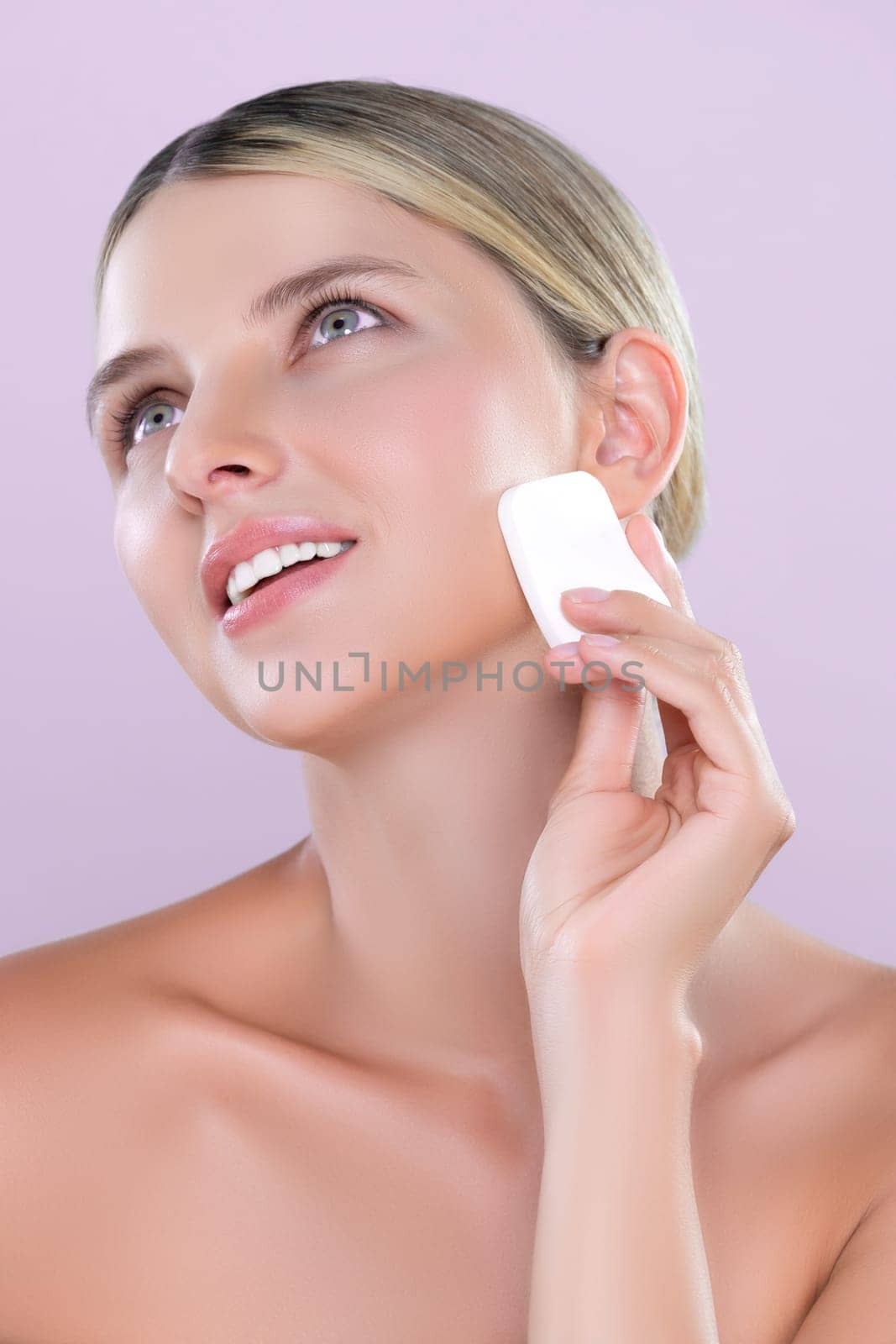 Closeup alluring beautiful female model applying powder puff for facial makeup concept. Portrait of flawless perfect cosmetic skin woman put powder foundation on her face in pink isolated background.