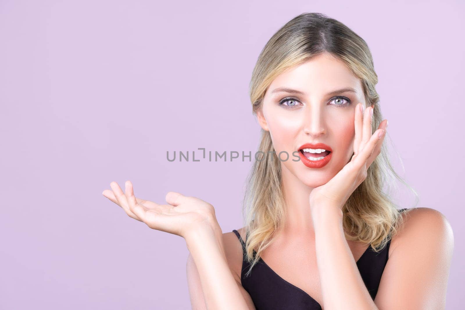 Beautiful blonde hair woman posing alluring hand gesture indicate product on pink isolated background copyspace. Perfect clean skin girl making skincare product advertisement.