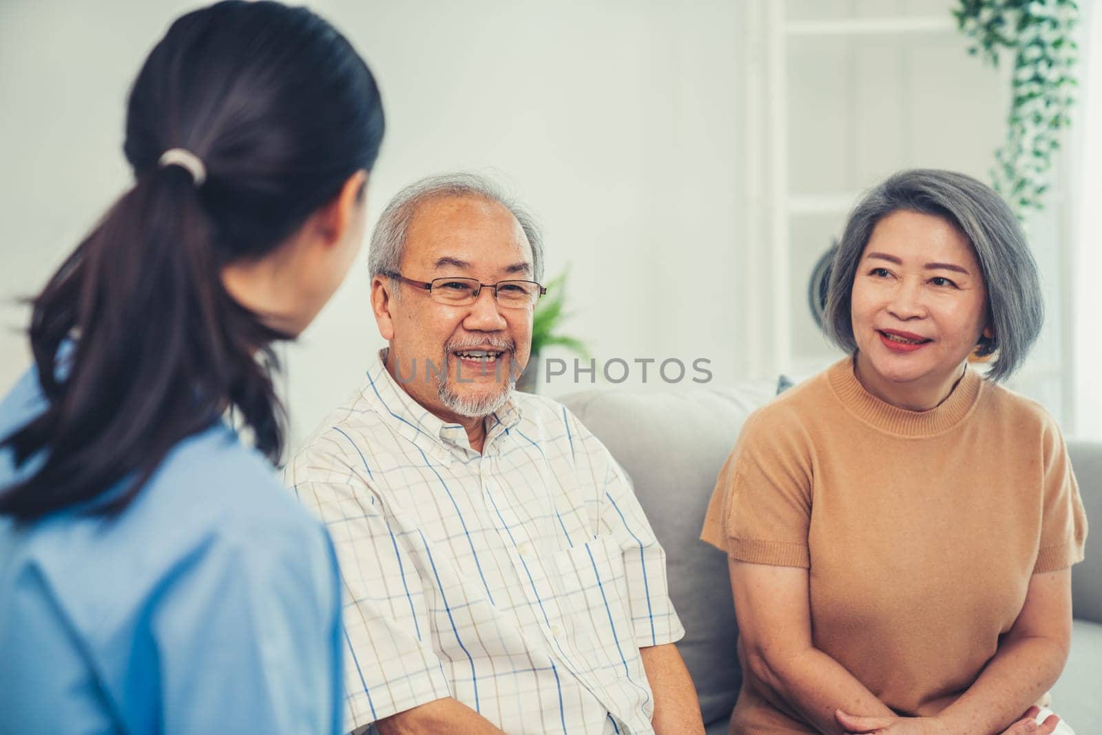 Female doctor visiting and talking to her contented senior couple at their home by biancoblue