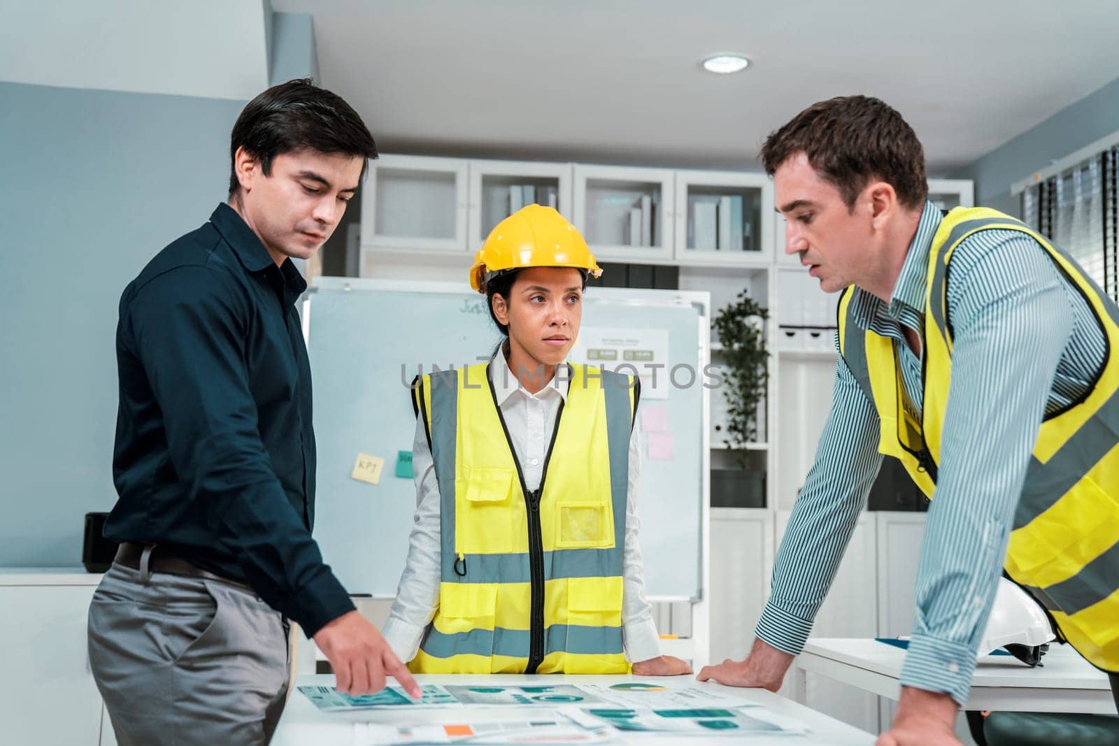 A group of competent engineers and employer discuss plans in the office. Architectural investor, businessman, and engineer discussing blueprints.