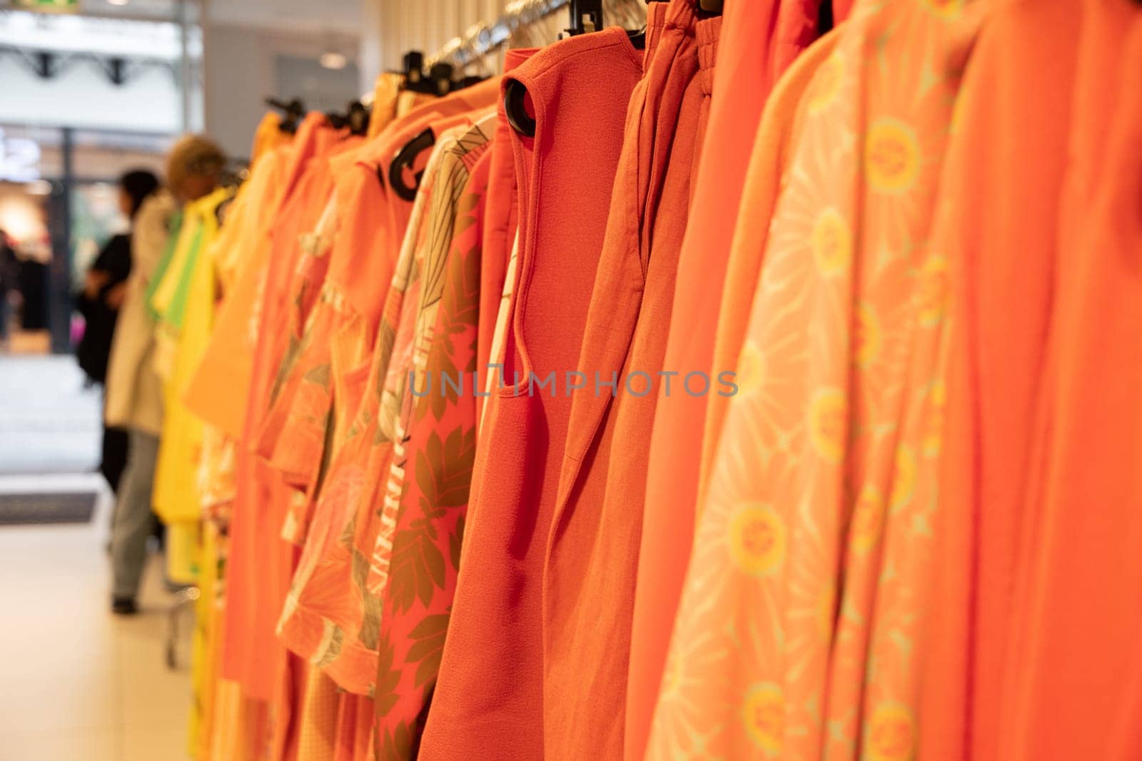 different models orange blouses in second hand grouped in the same color on a hanger, bright summer colors of fashion clothes, High quality photo