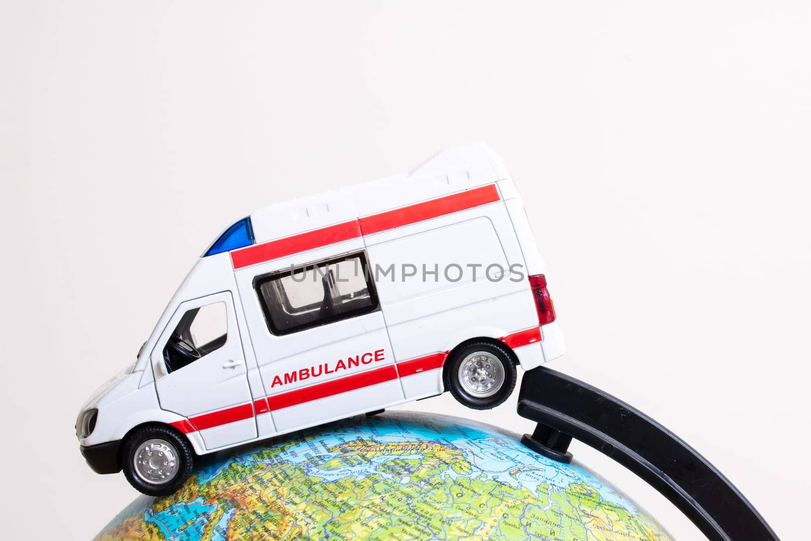 Globe and ambulance toy car on gray background close up