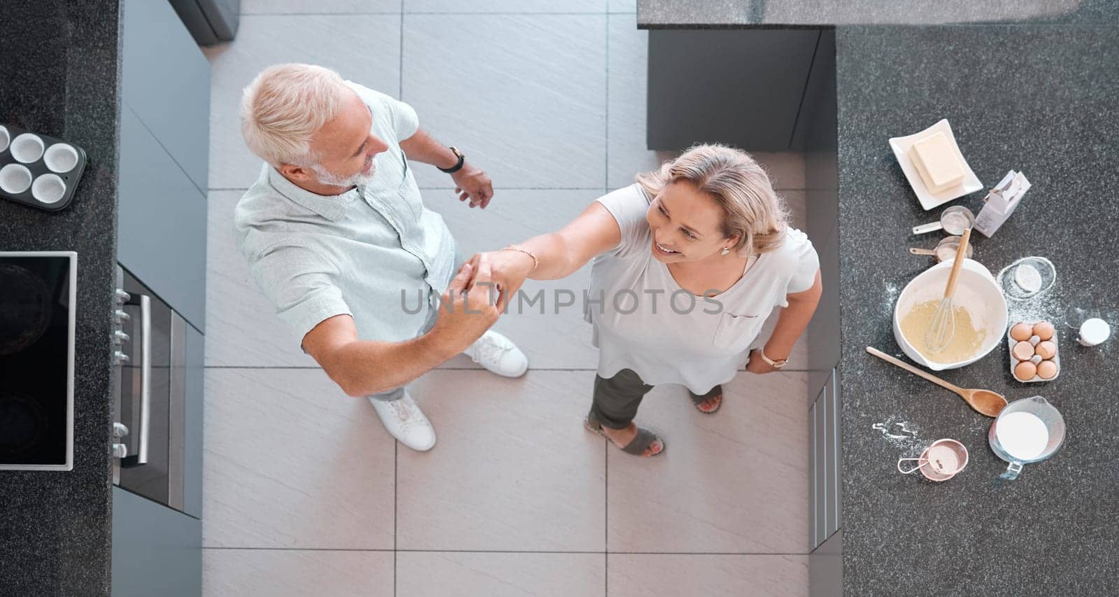 Top view dancing and senior couple in kitchen having fun, bonding and enjoy retirement together. Love, romance and aerial of happy elderly man and woman cooking, baking and dance on weekend at home.