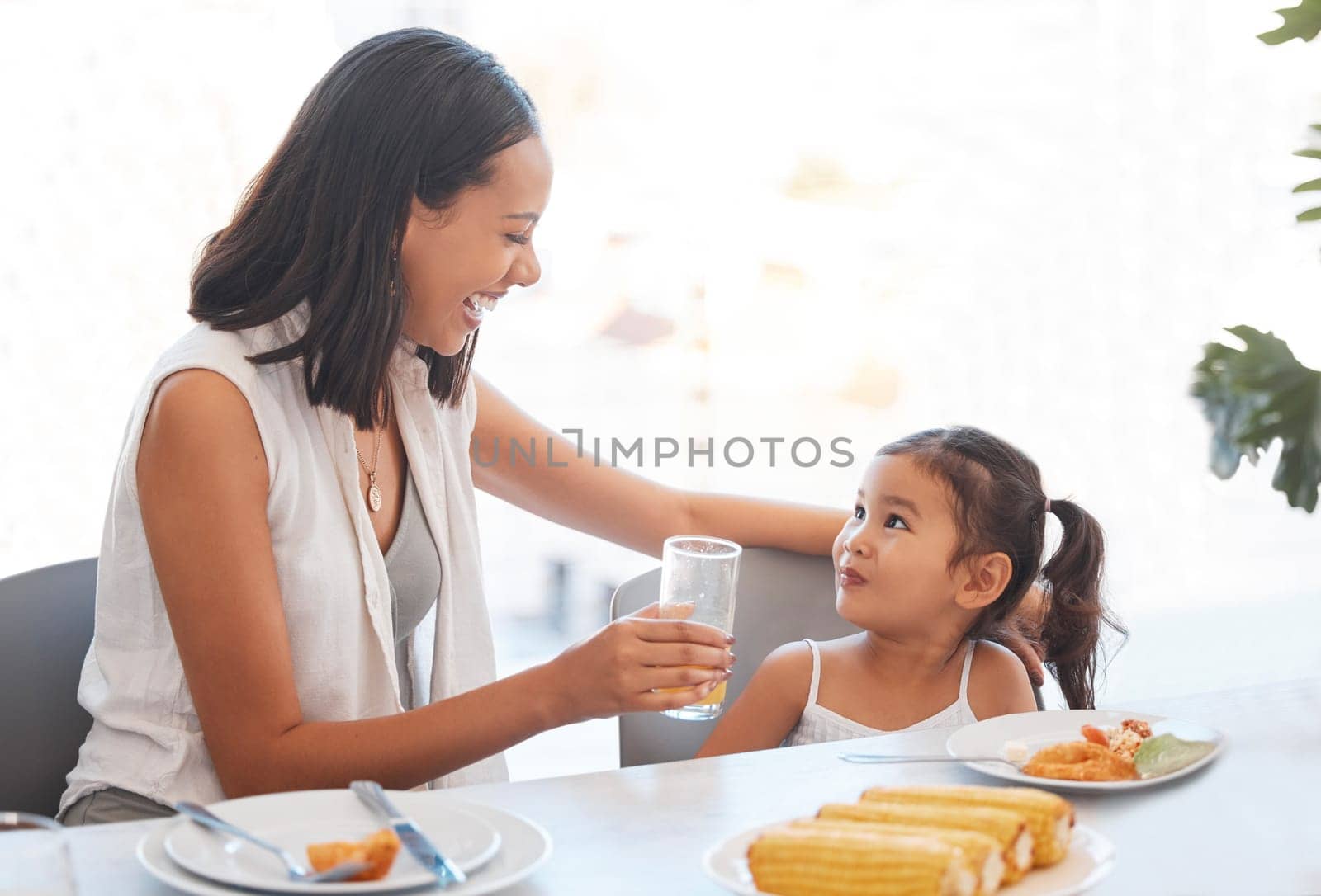 Woman, food and eating at home for health, wellness and diet nutrition at the dining table. Meal, lunch and mother and daughter eat and drink juice together for hungry child in the family home by YuriArcurs