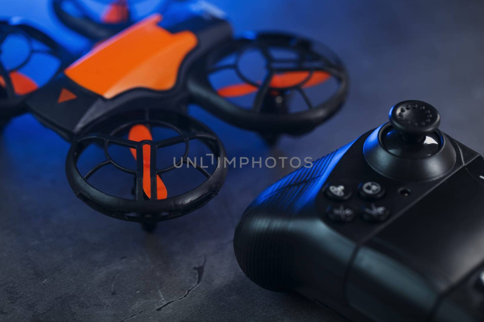 Gaming orange mini drone on a dark background for control from a gamepad