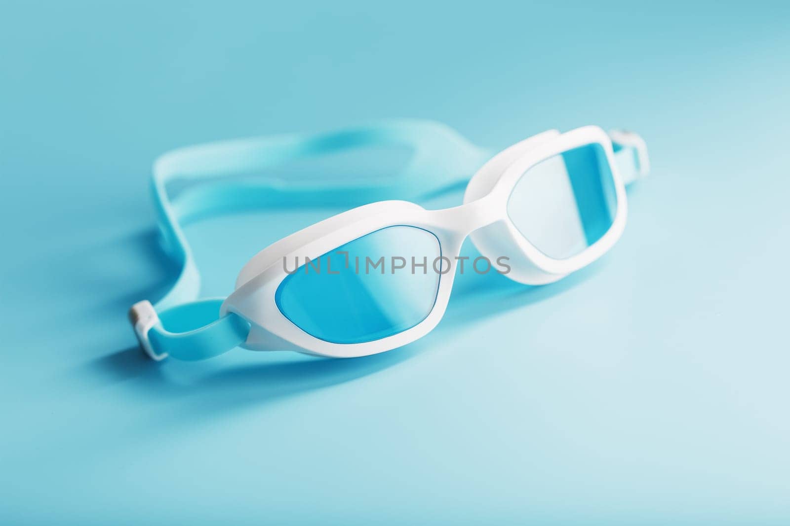 White swimming goggles on a blue background in a minimalist style with free space