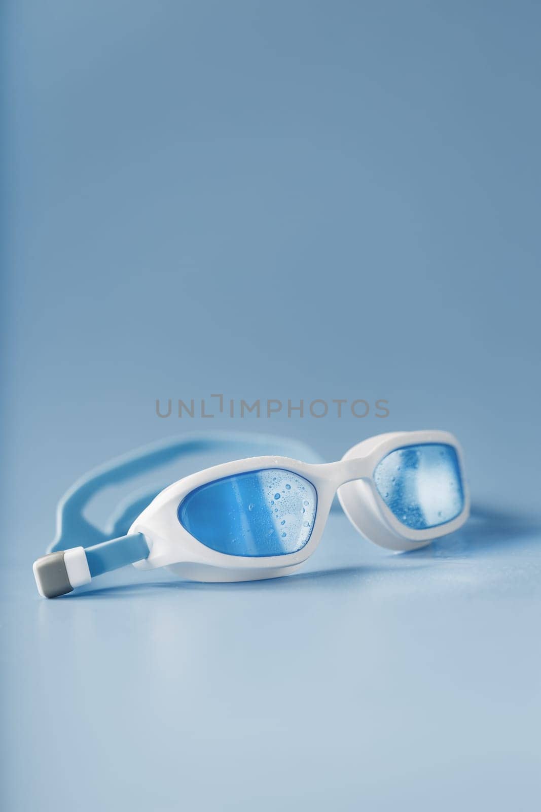 White swimming goggles on a blue background in a minimalist style with free space