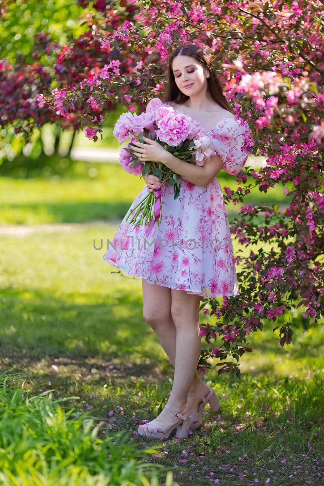 the girl, closed her eyes, stands with a large bouquet of peonies, by Zakharova