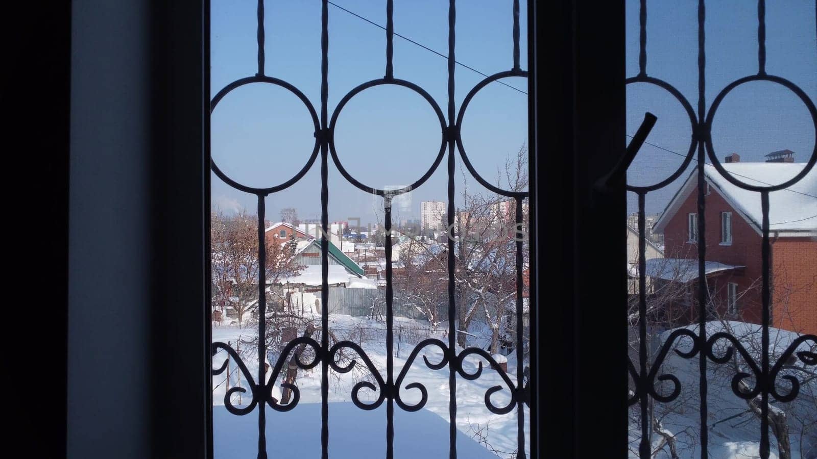 View of the old courtyard from the window of a private house. Snow outside the window. The camera zooms in on the window through the dark room. 4k