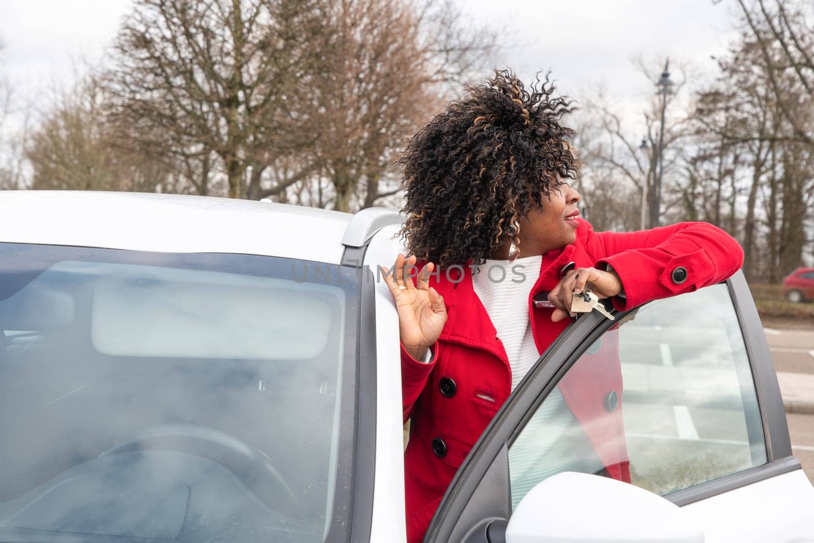 Confident african american businesswoman in trendy clothes standing near new white car, High quality photo