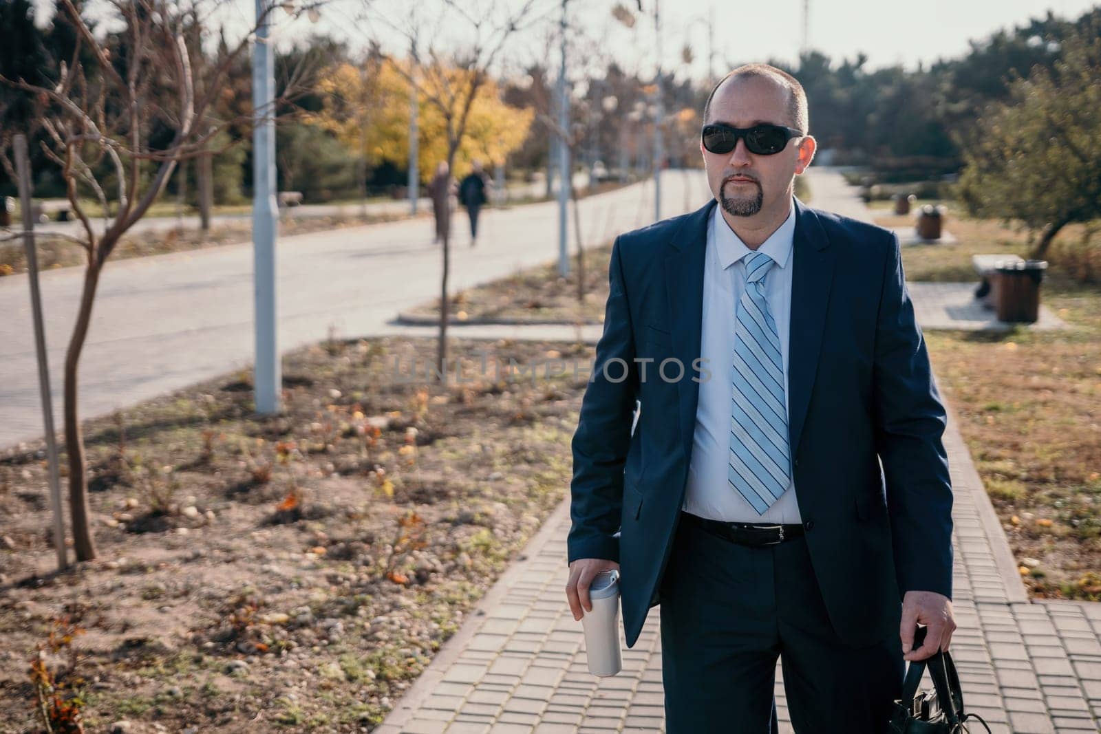 Mature entrepreneur drink coffee in autumn park. Senior executive rest in city park.