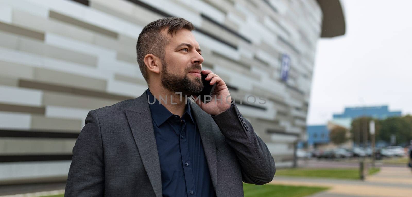 pensive male architect speaks on the phone on the background of the building.