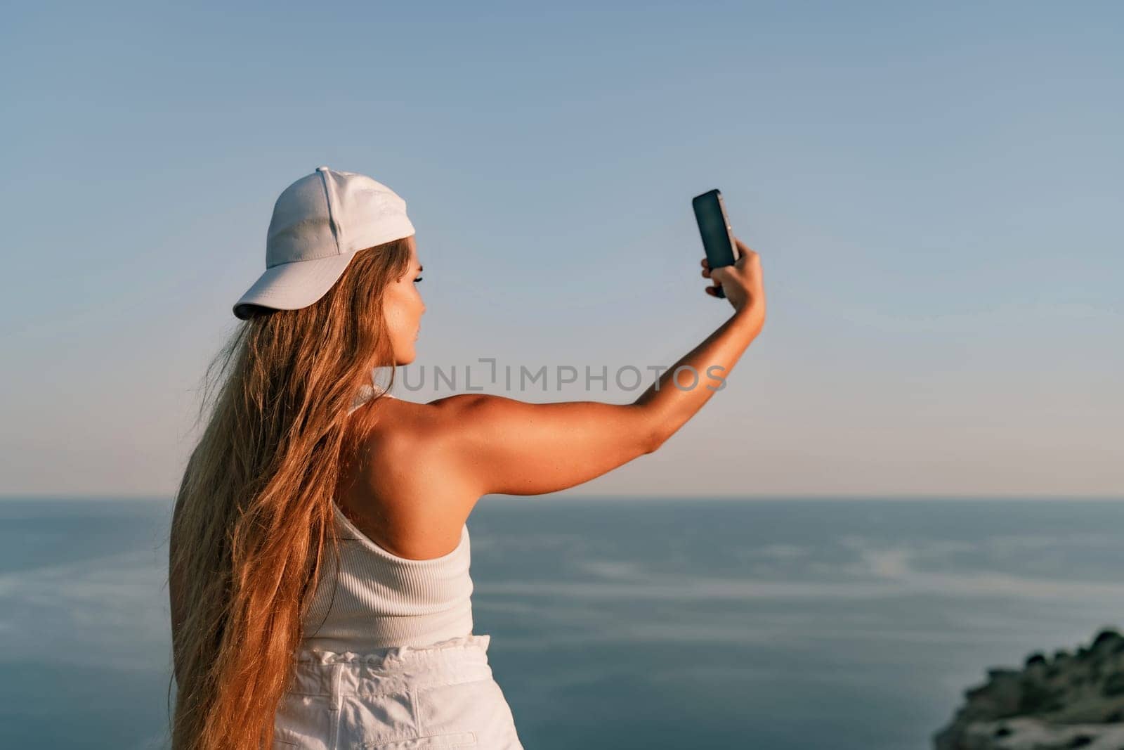 Selfie woman in cap and tank top making selfie shot mobile phone post photo social network outdoors on sea background beach people vacation lifestyle travel concept