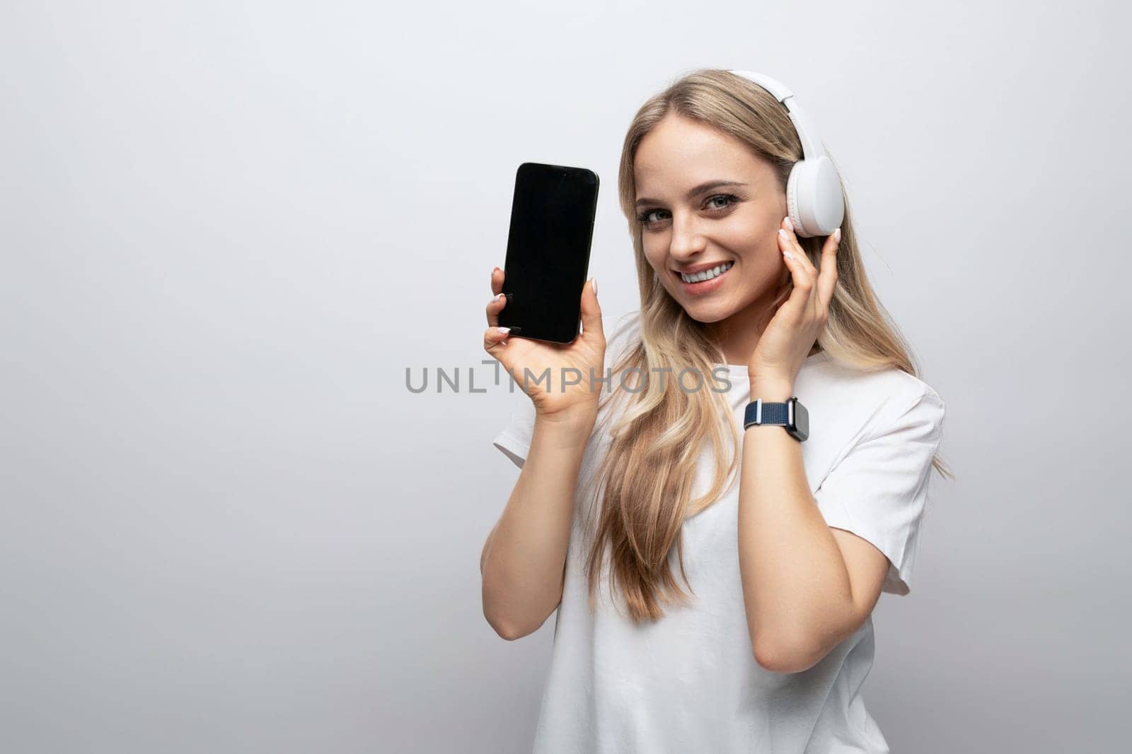 woman in wireless headphones with vertically positioned blank screen on phone with mockup isolated on white background by TRMK