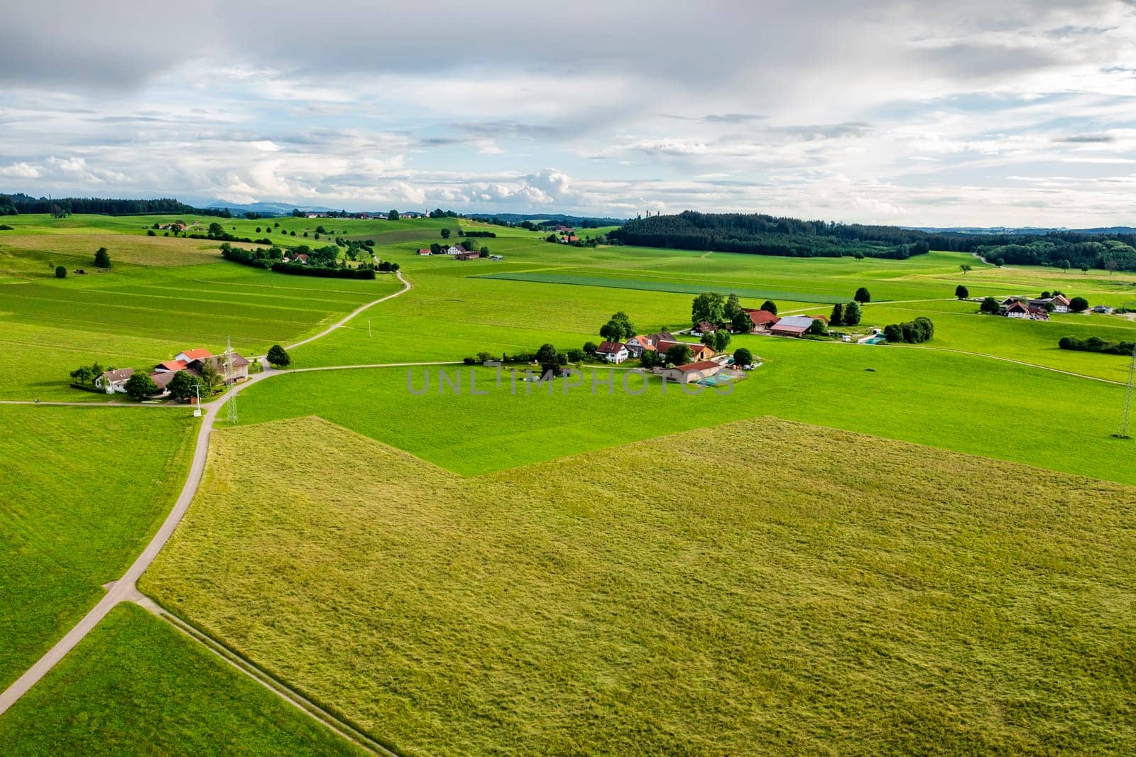 Amazing wide aerial view from drone of beautiful green countryside, fields, road, and farms.