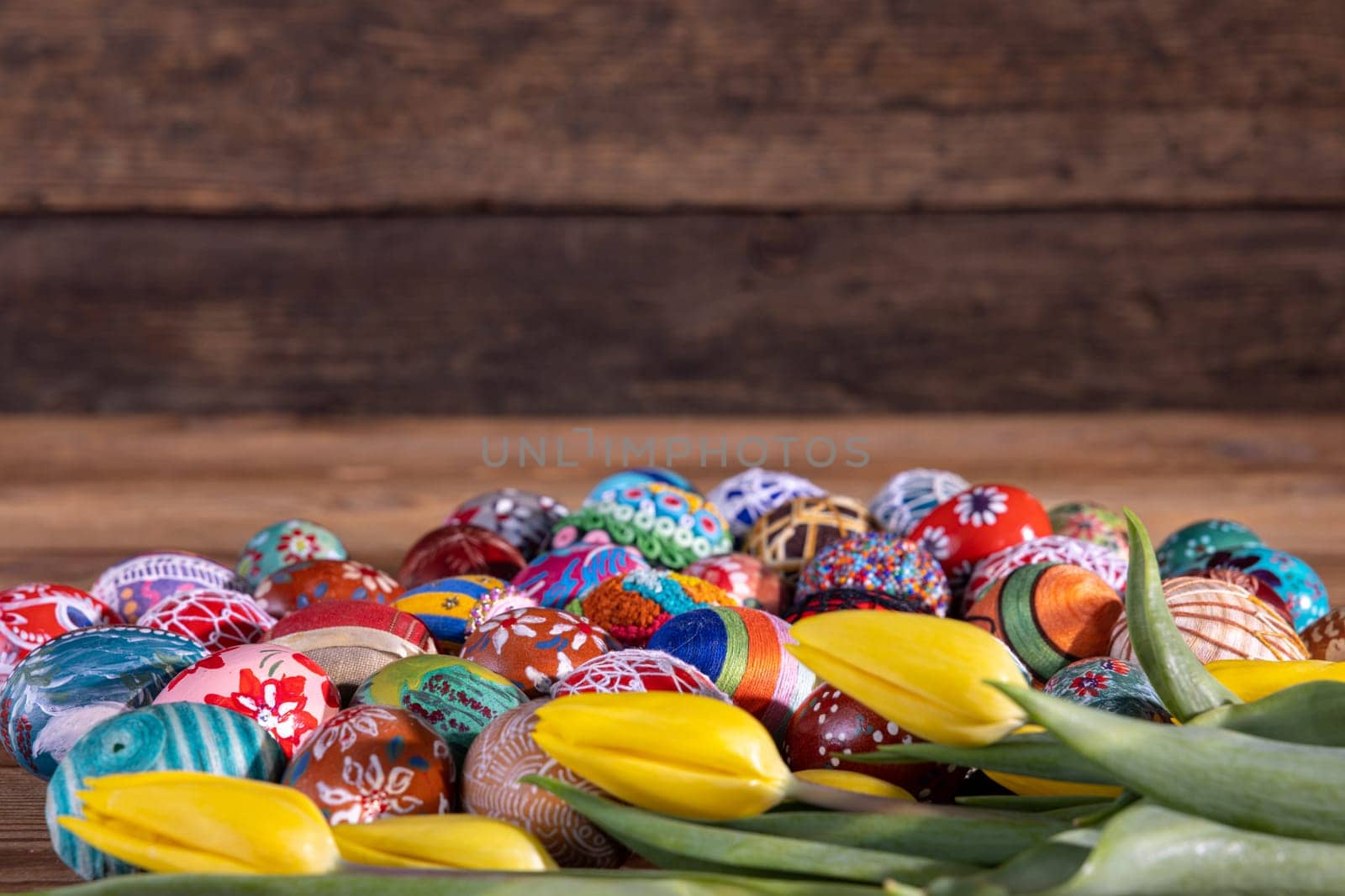 Easter composition allowing you to put your own graphic content on a free field. Yellow tulips and Easter eggs in the foreground and fuzzy boards in the background.