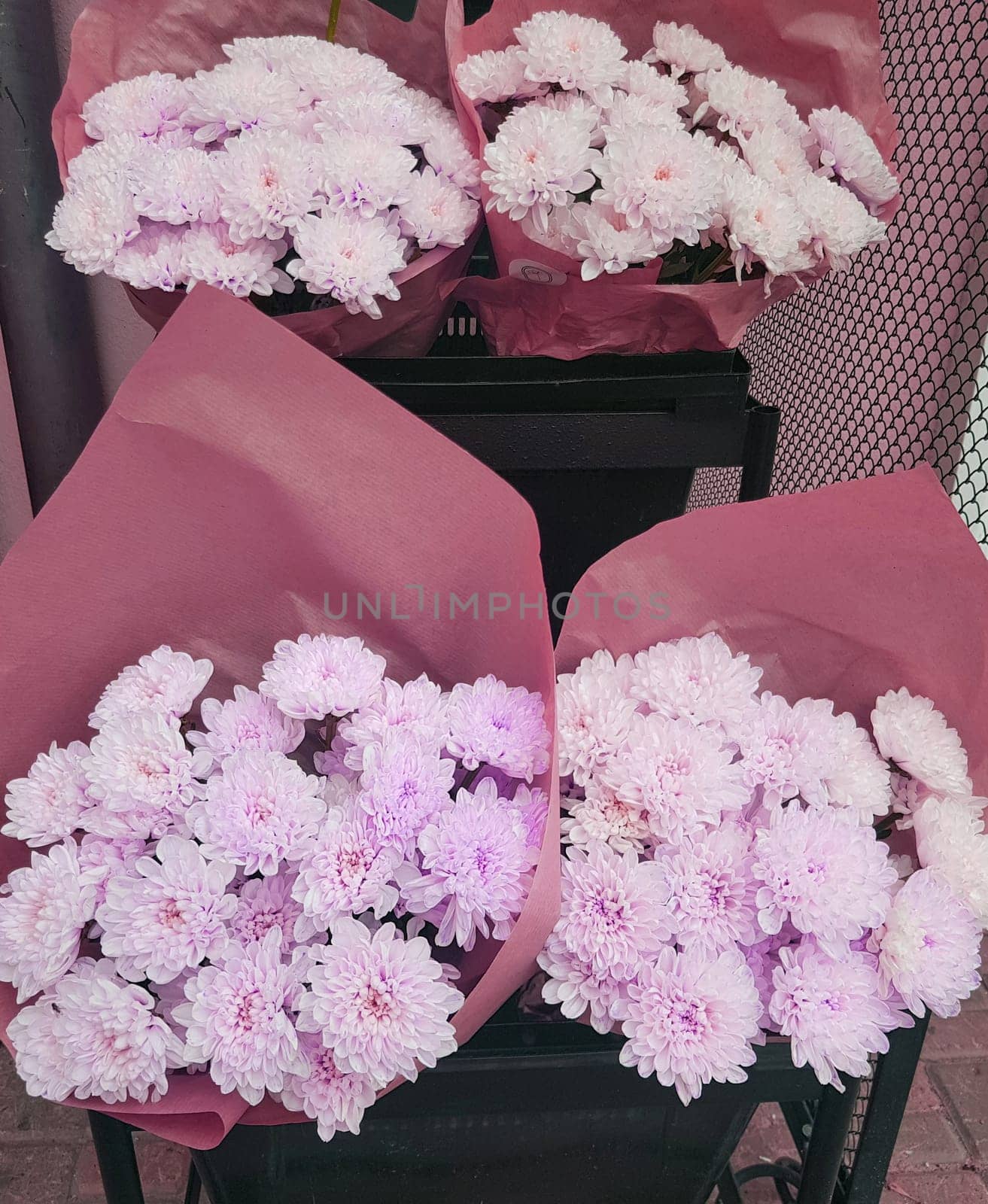 Beautiful gift bouquets of chrysanthemums in brown kraft paper, on the counter of a flower shop, vertical.