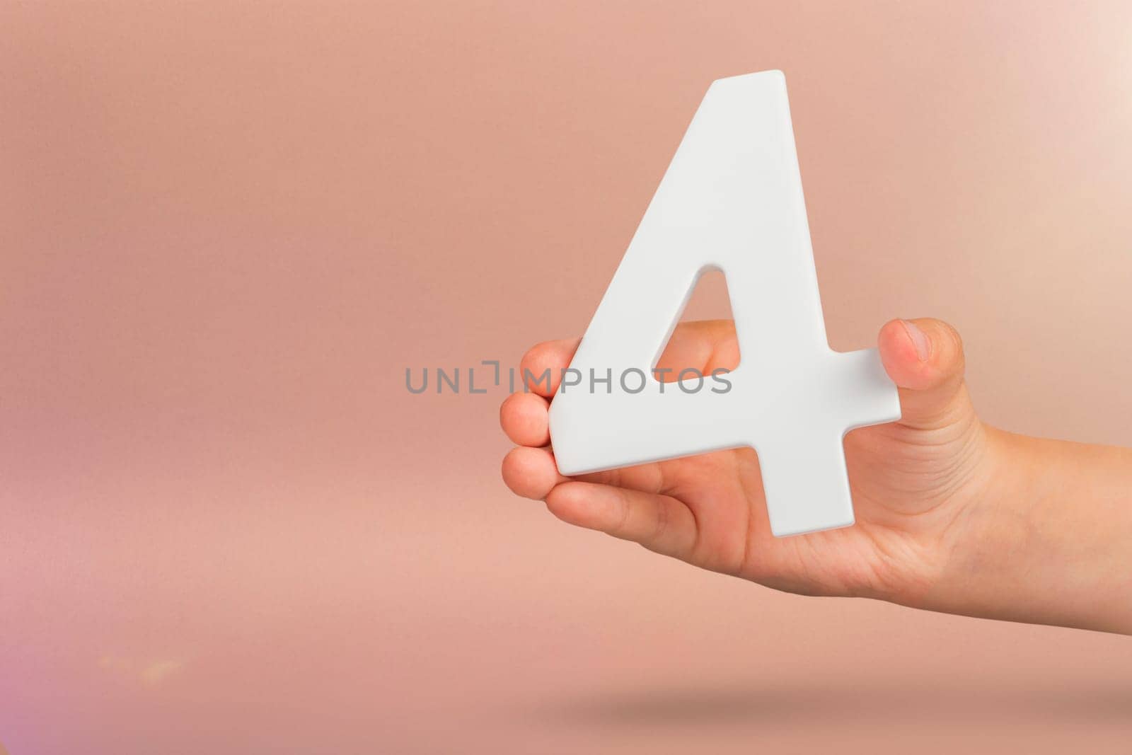 number four in hand. Hand holding white number 4 on red background with copy space. Concept with number four. Birthday 4 years, fourth grade, four day work week.