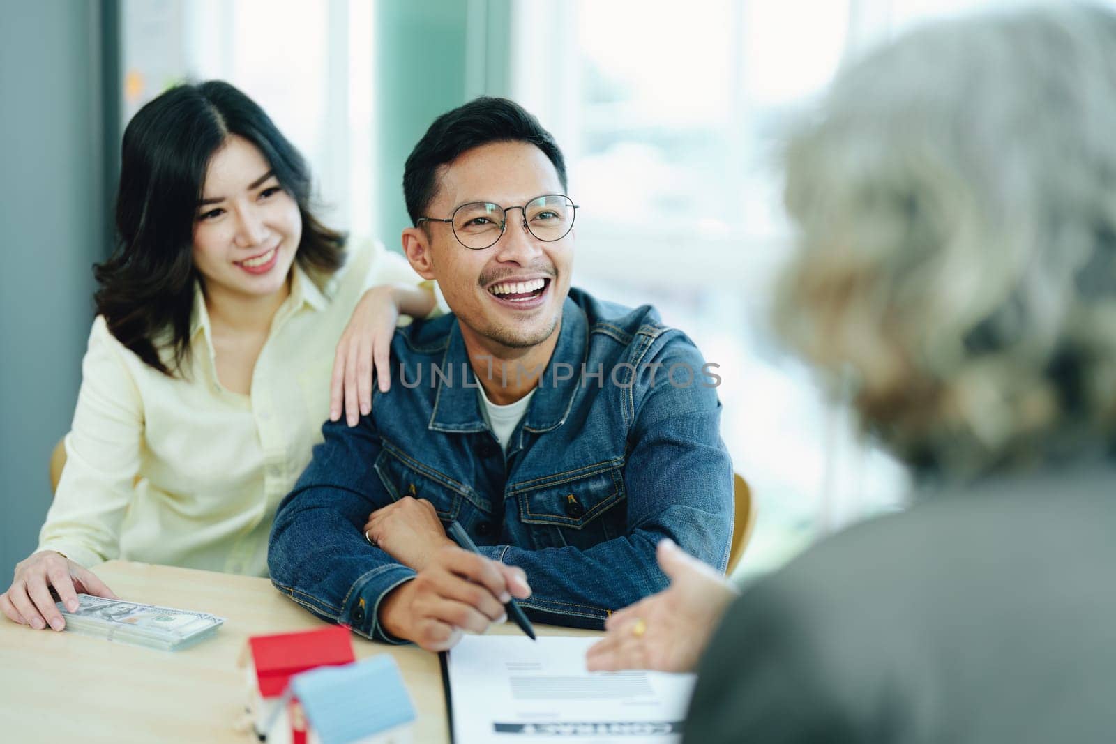 Guarantee Insurance Sign a contract, couple a smiling couple is signing a contract to invest in real estate with the Mortgage officer with the bank by Manastrong