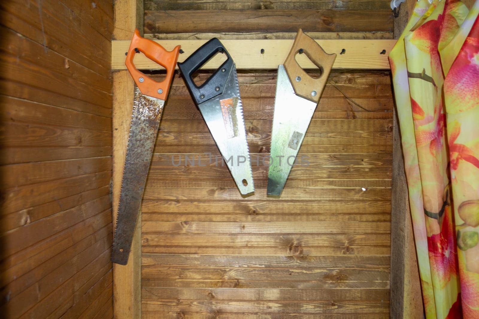 Garden tools old saws hanging on the wooden wall of the outbuilding. Tool storage.