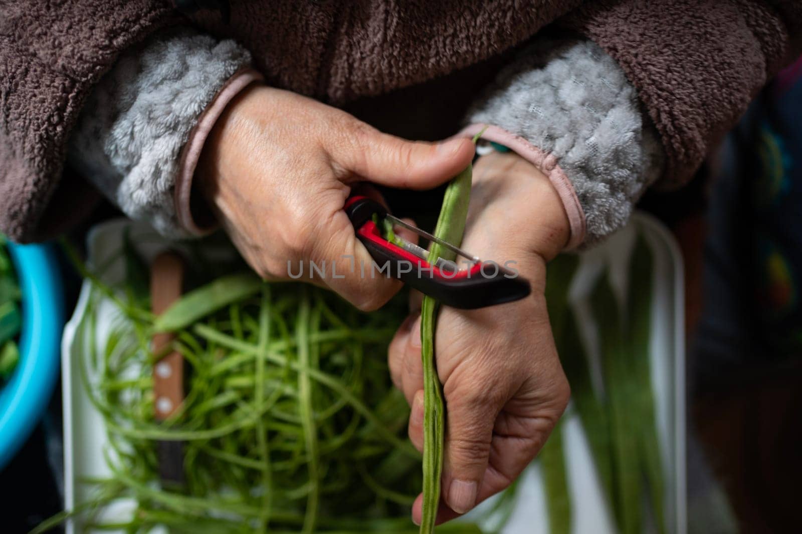 old woman hands peeling fresh organic green beans.