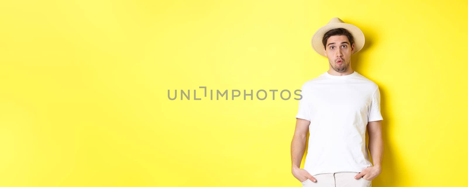 Confused guy traveller in straw hat looking puzzled, stare at camera, standing over yellow background by Benzoix