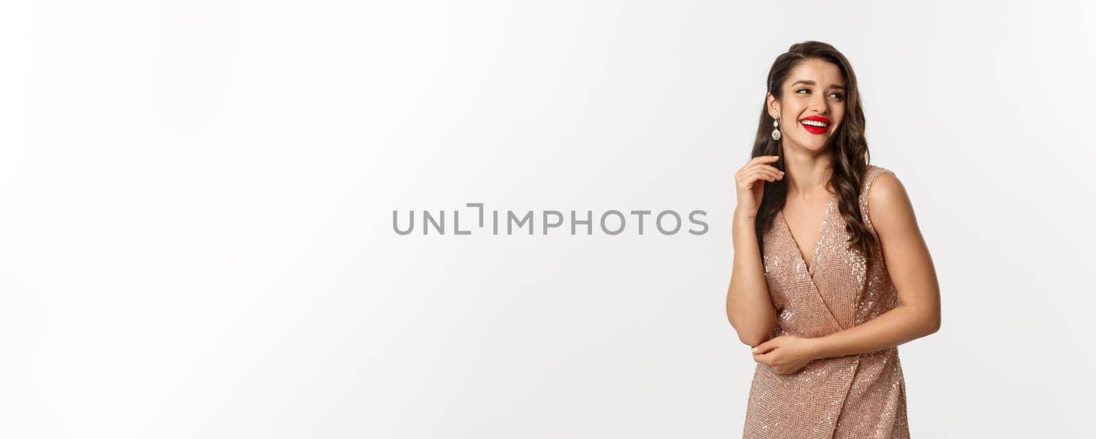 Elegant woman standing in evening dress and makeup, laughing and celebrating New Year, wearing outfit for formal party, standing over white background.