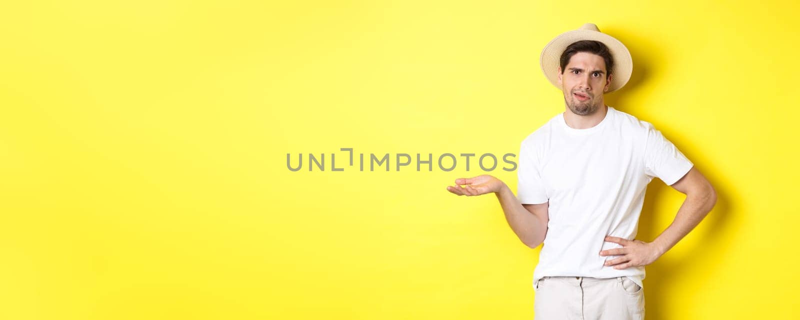 Concept of tourism and summer. Young skeptical tourist complaining, looking judgemental, standing over yellow background by Benzoix