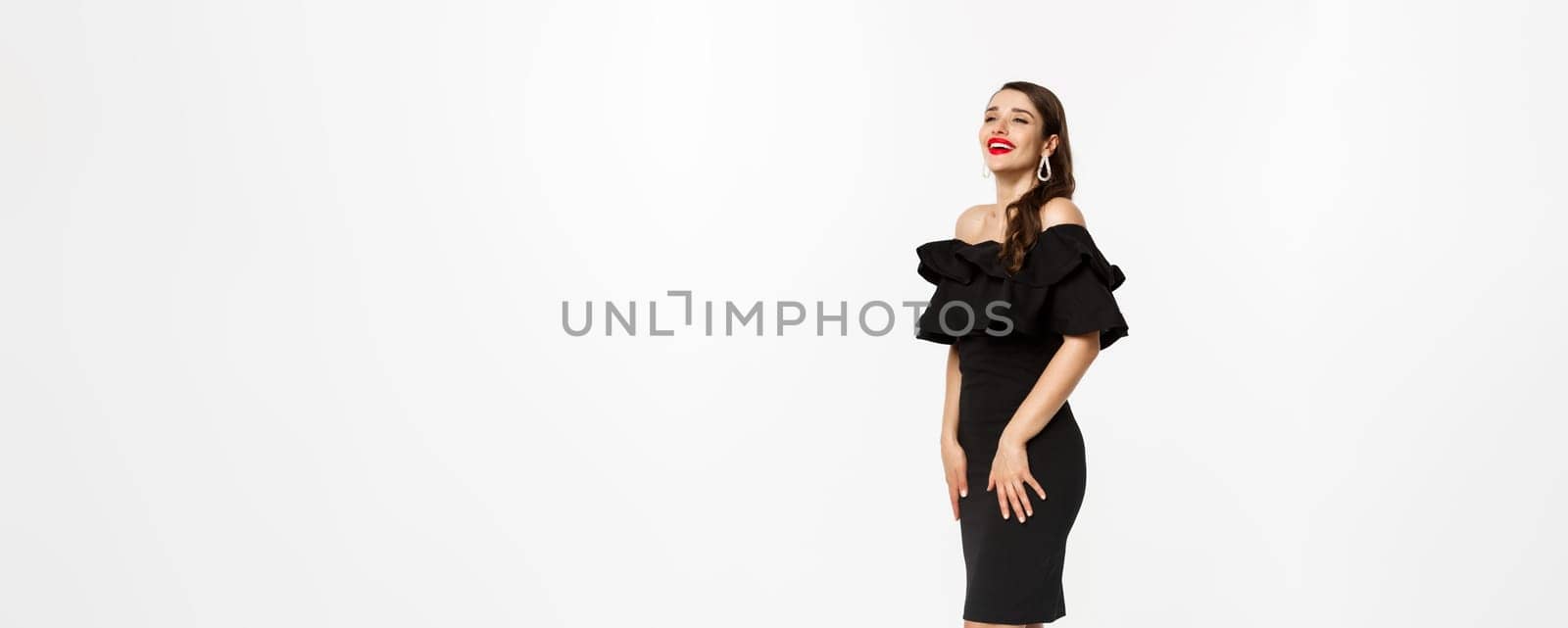 Vertical view of beautiful young woman in luxurious dress, red lips and jewelry, standing with christmas gifts on white background, standing over white background by Benzoix