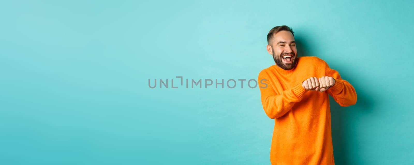 Happy man dancing and celebrating success, feeling like winner, smiling and rejoicing, light blue background.