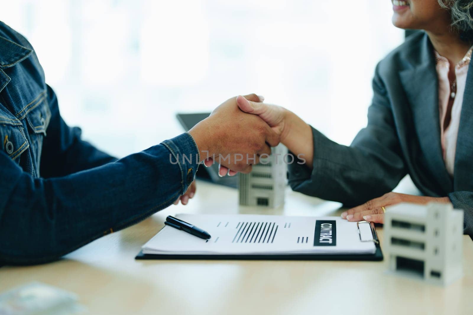 The bank's Mortgage Officers shake hands with customers to congratulate them after signing a housing investment loan agreement by Manastrong