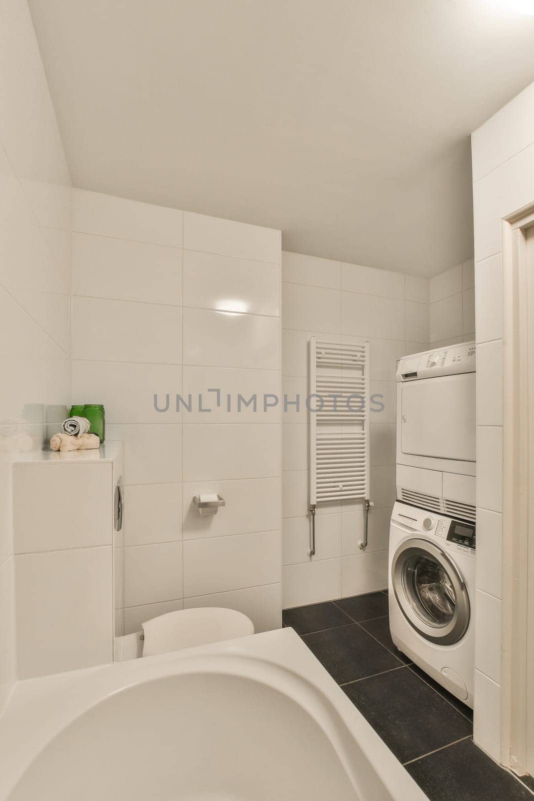 a laundry room with a washer and dryer in the corner, next to a bathtub on the floor