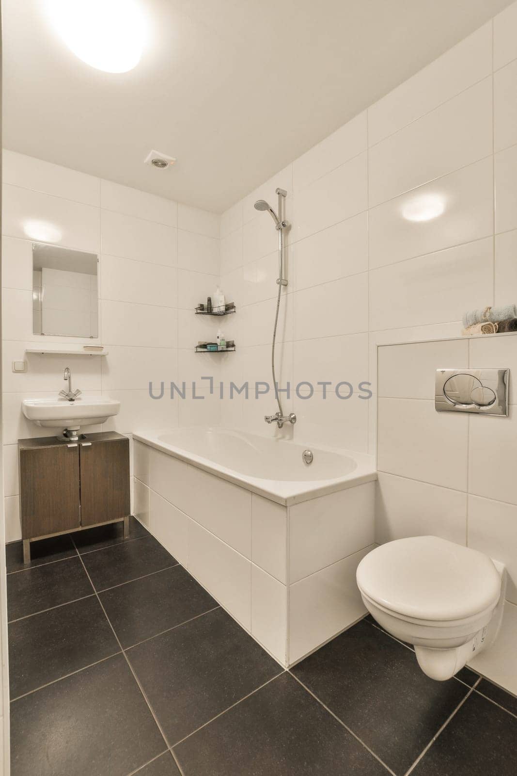 a white bathroom with black tile flooring and wall to wall tiles on the walls there is a toilet in the shower stall