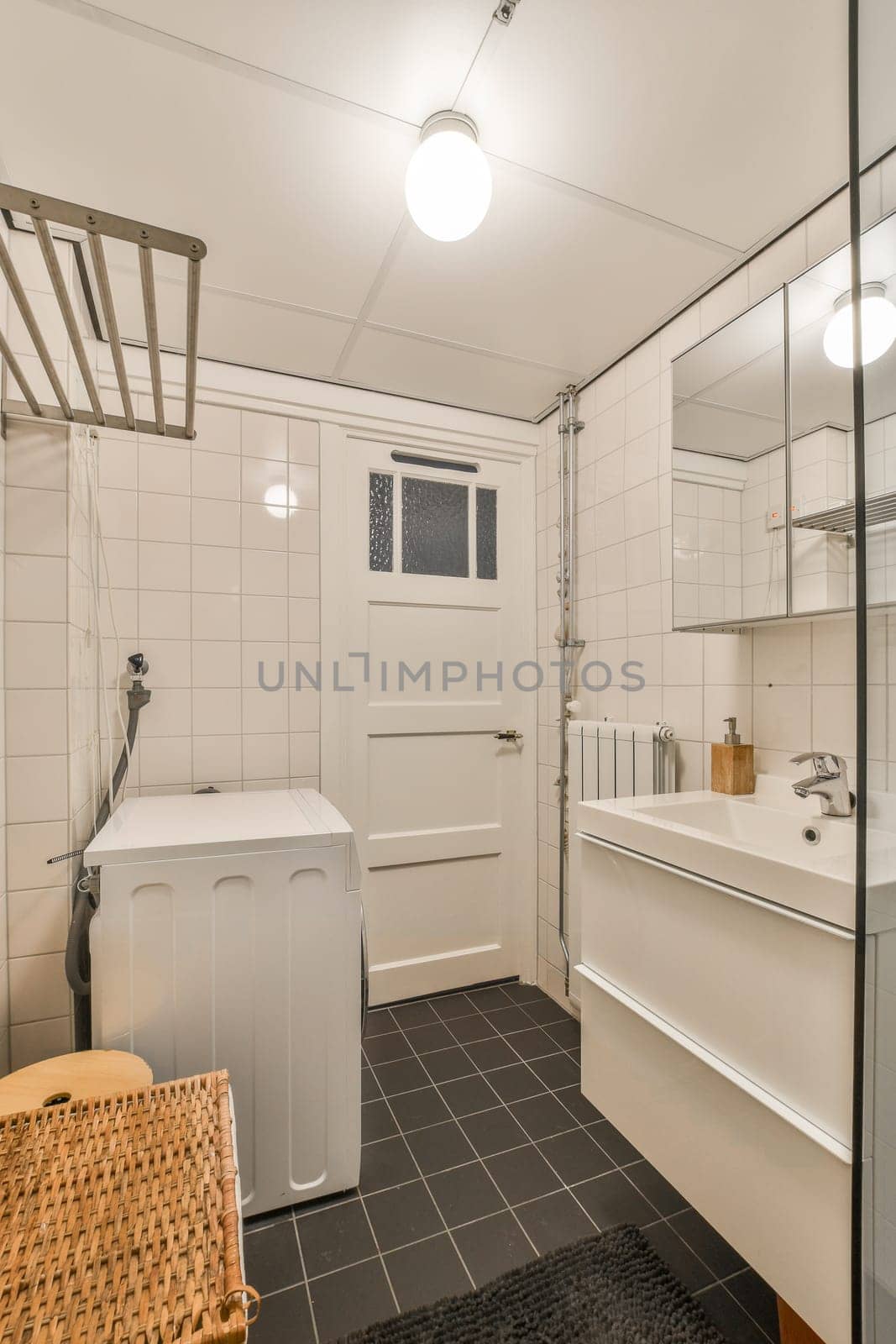 a bathroom with black tile and white tiles on the floor, along with a washer and dryer in the corner