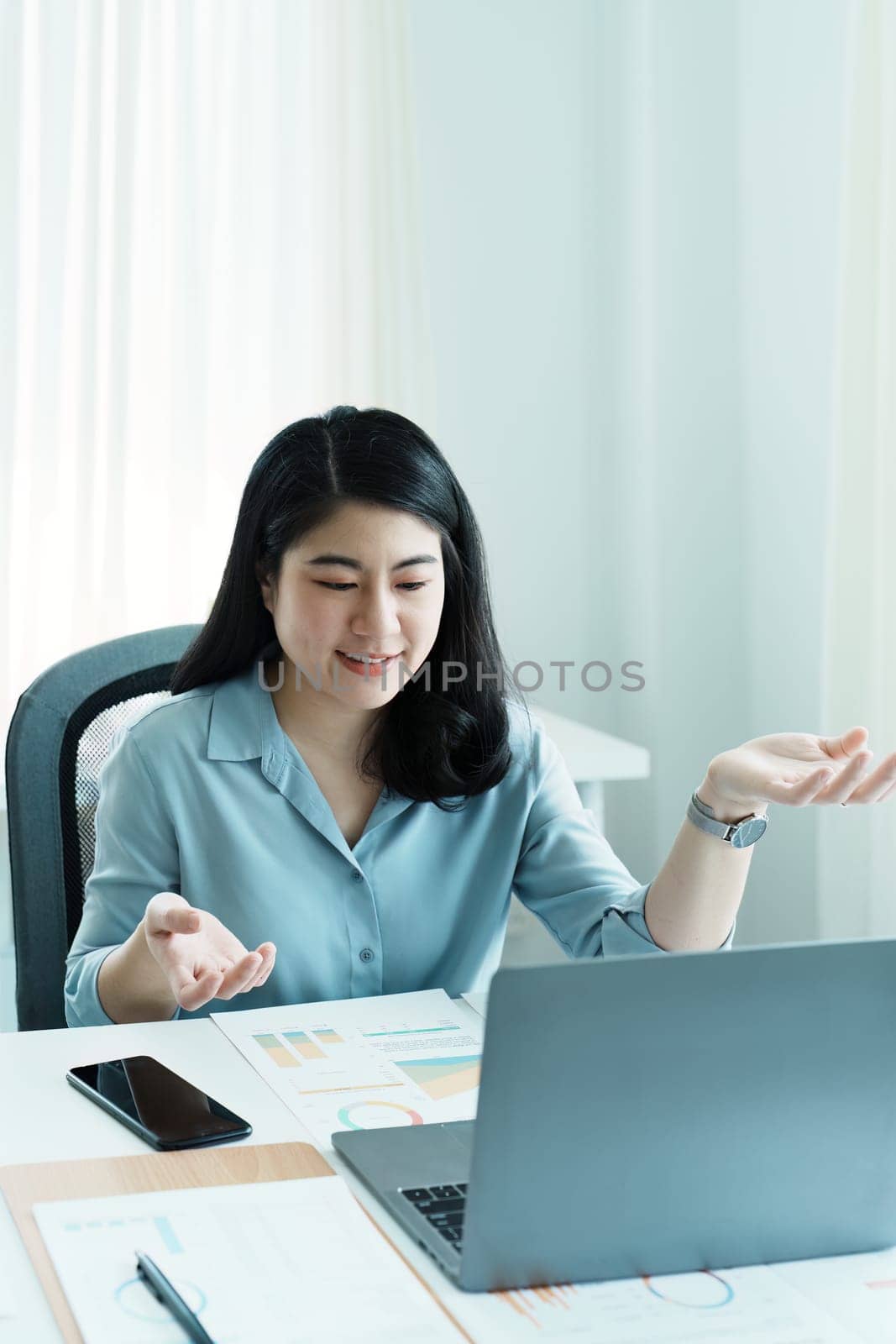 Portrait of a beautiful Asian teenage girl using computer for video conferencing at office by Manastrong