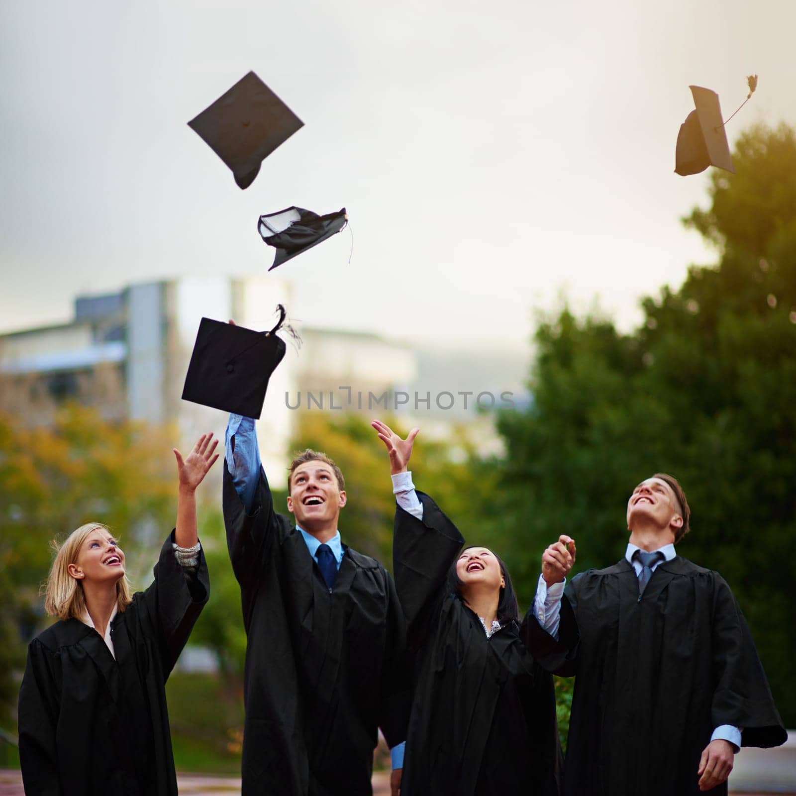 The tassel was worth the hassle. A group of students throwing their caps into the air after graduation. by YuriArcurs