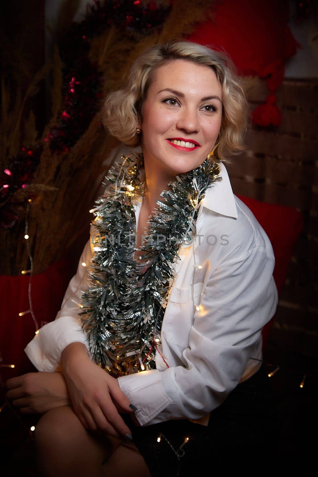 Portrait of a beautiful laughing funny blonde girl with light of garland on a dark background before Christmas or New Year by keleny