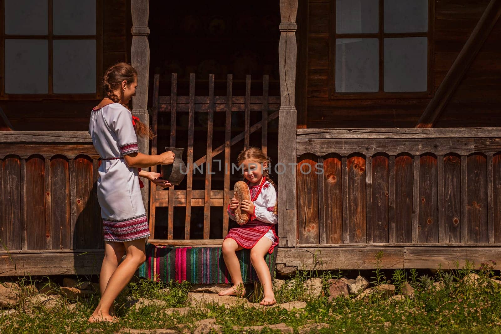 mother and daughter in Ukrainian folk dresses on the threshold of the house.