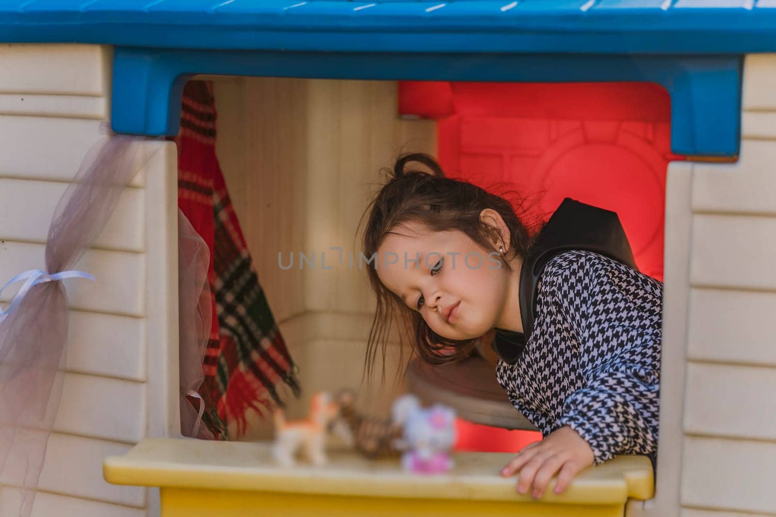 girl is playing in her little house, looking out the door