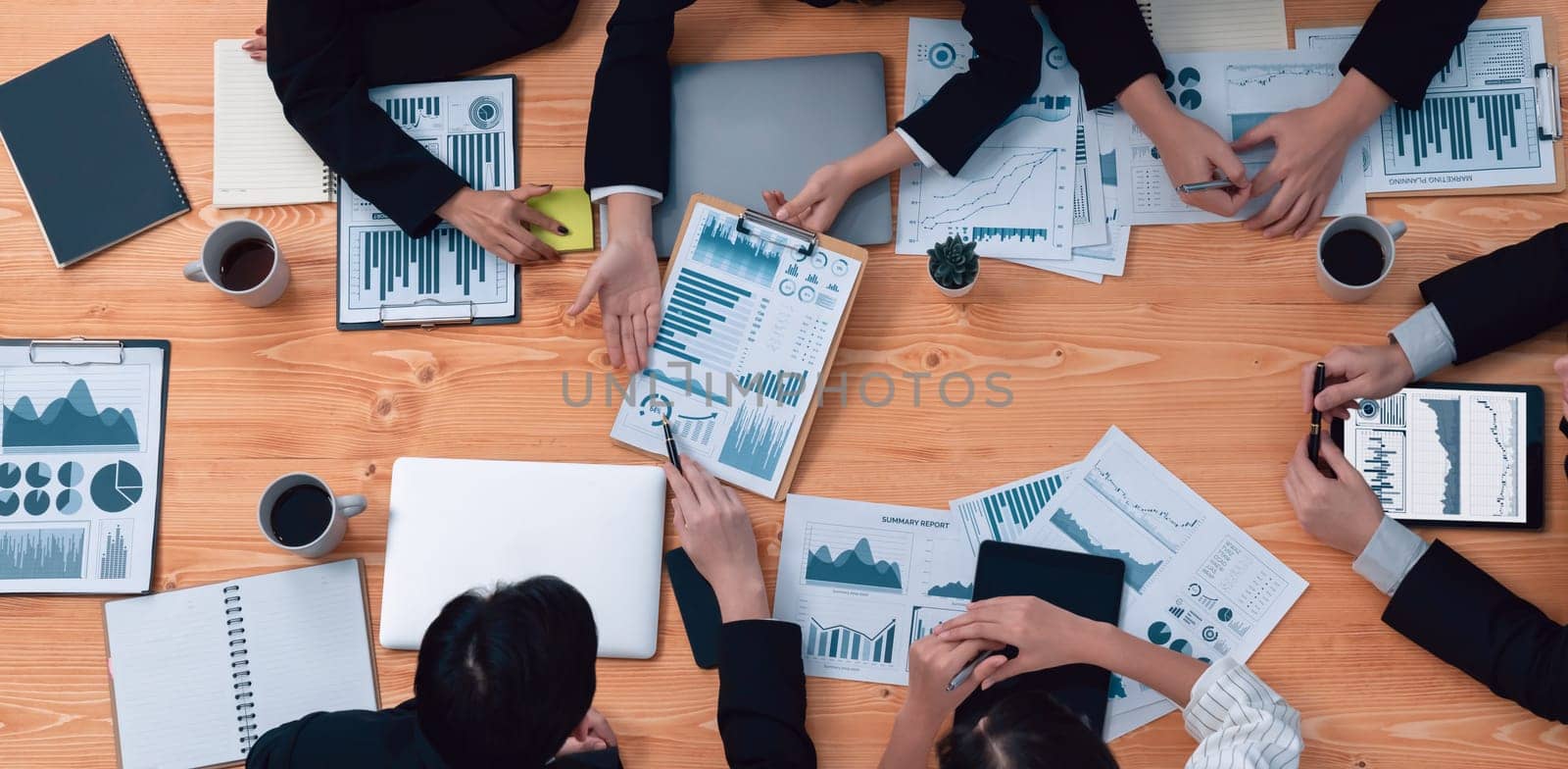 Top-view closeup business team of financial data analysis meeting with business intelligence, report paper and dashboard on laptop. Business group people working together in harmony office.
